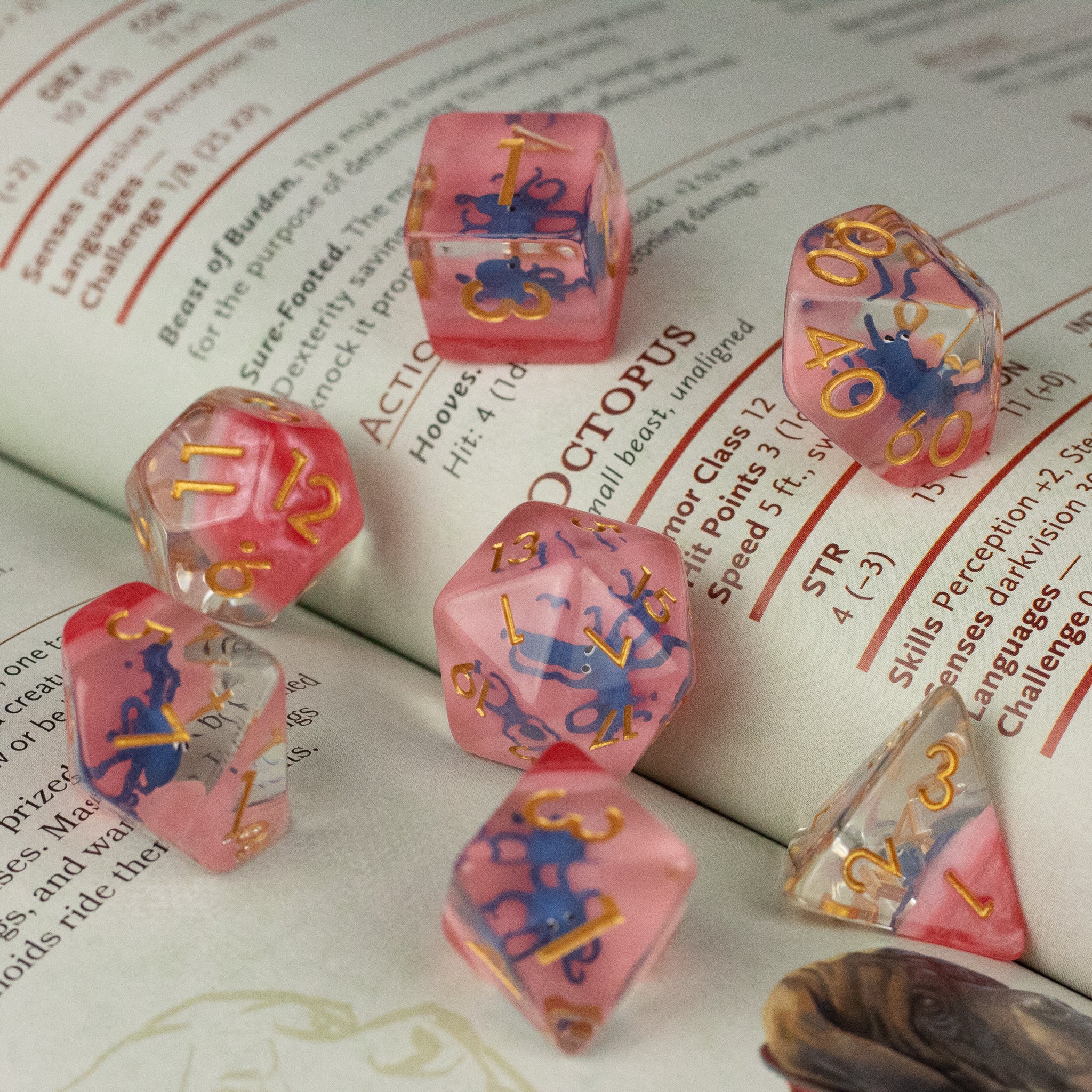 Dark Blue Octopus Dice Set - Set of translucent dark blue and pink polyhedral dice with gold numbering, featuring octopus designs inside each die.