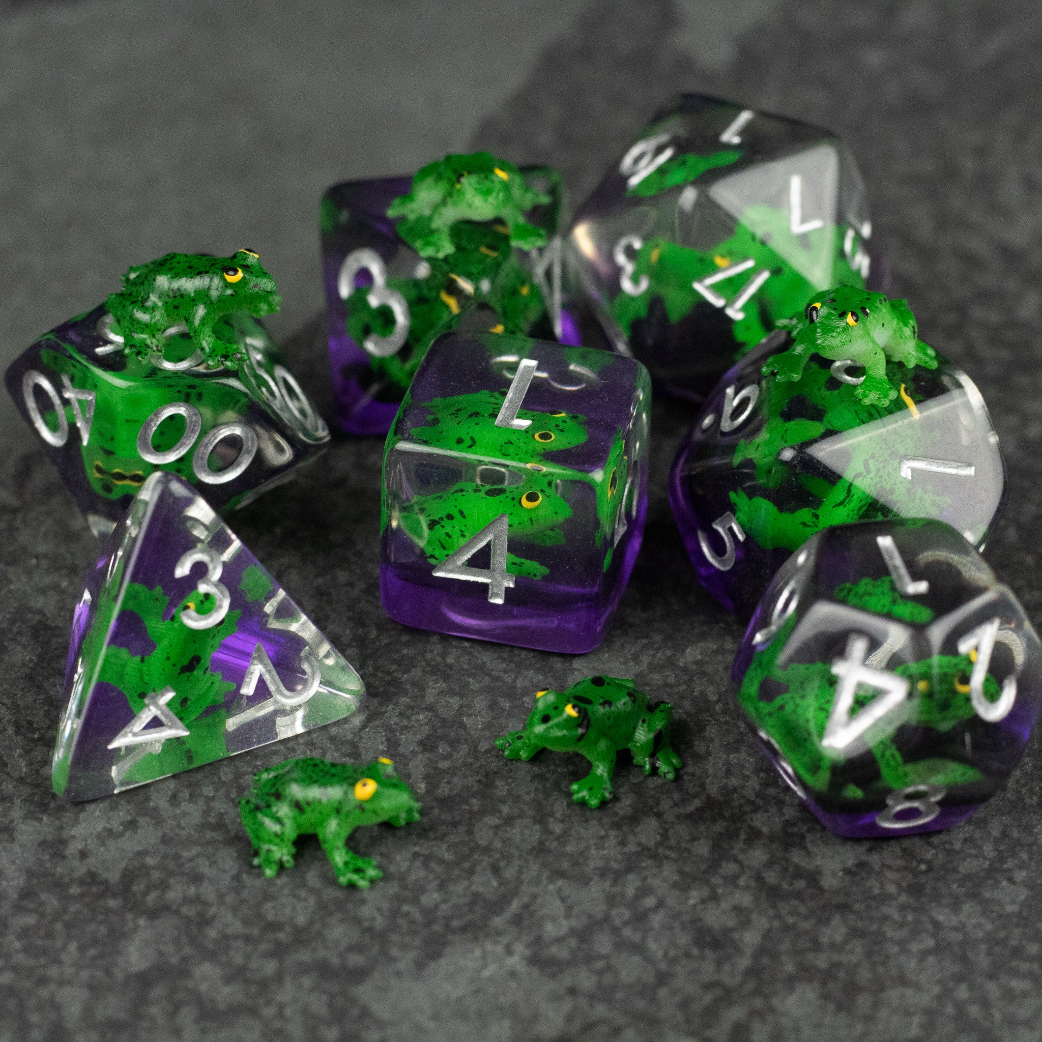 Green Frog Dice Set - Purple and clear polyhedral dice set with embedded green frog figurines and white numbers.