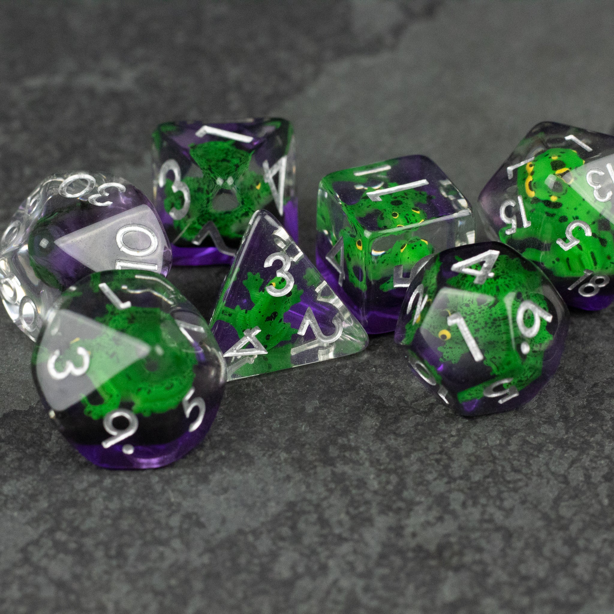 Green Frog Dice Set - Set of seven polyhedral dice with green and purple translucent design and white numbering.