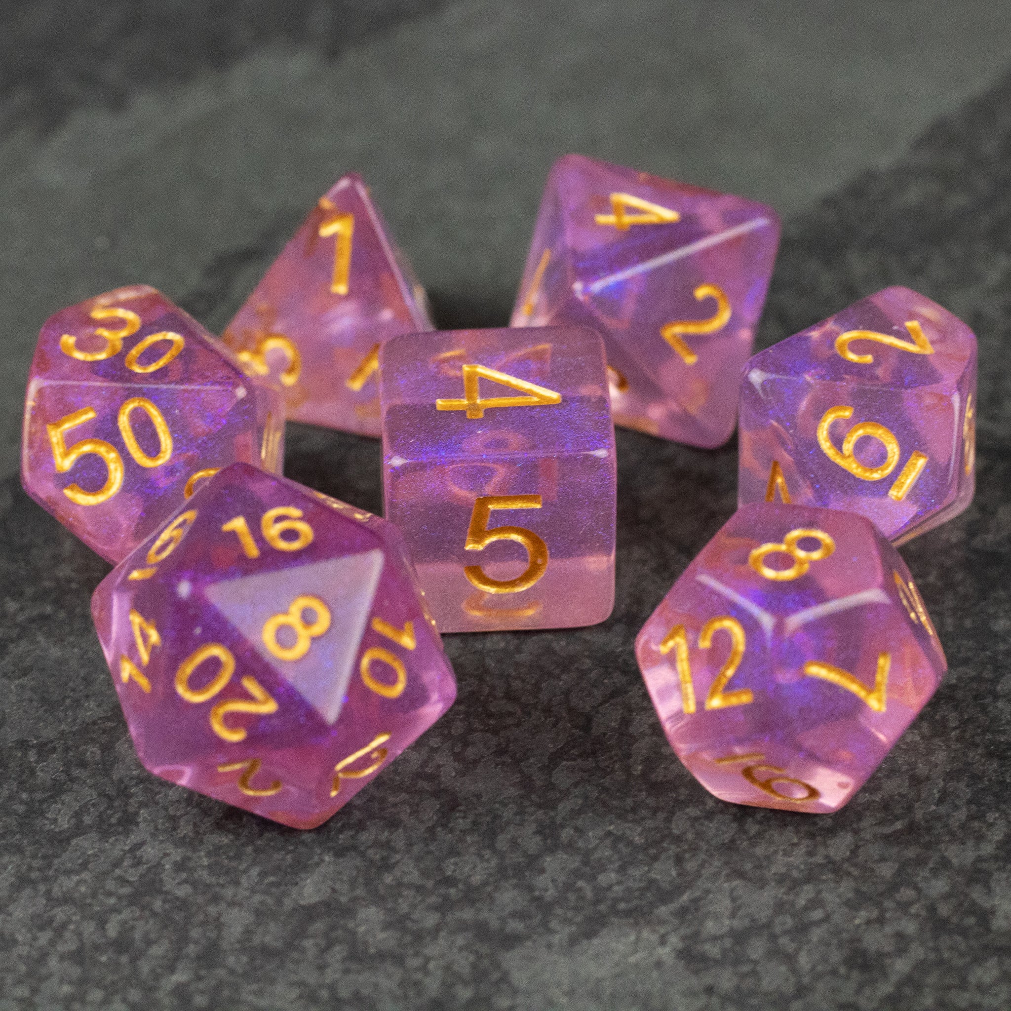 Purple Aura Glitter Dice Set - Purple translucent glitter dice set with gold numbers, featuring multiple polyhedral shapes.