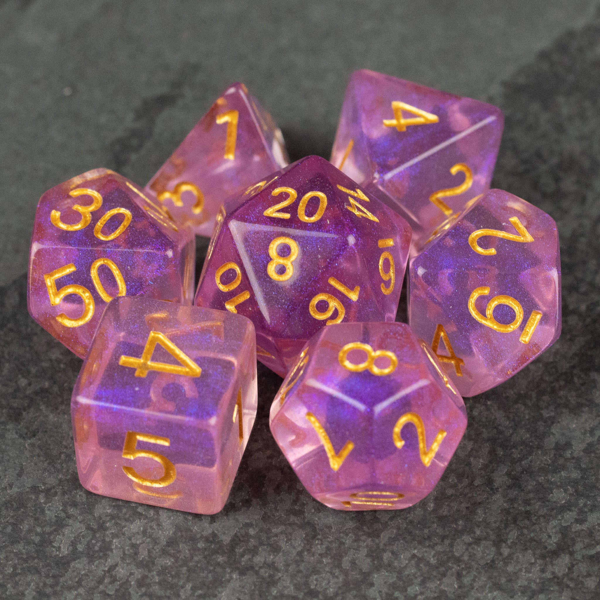 Purple Aura Glitter Dice Set - Purple translucent dice set with gold numbers, featuring d20, d12, d10, d8, d6, and d4 styles with glitter effect.