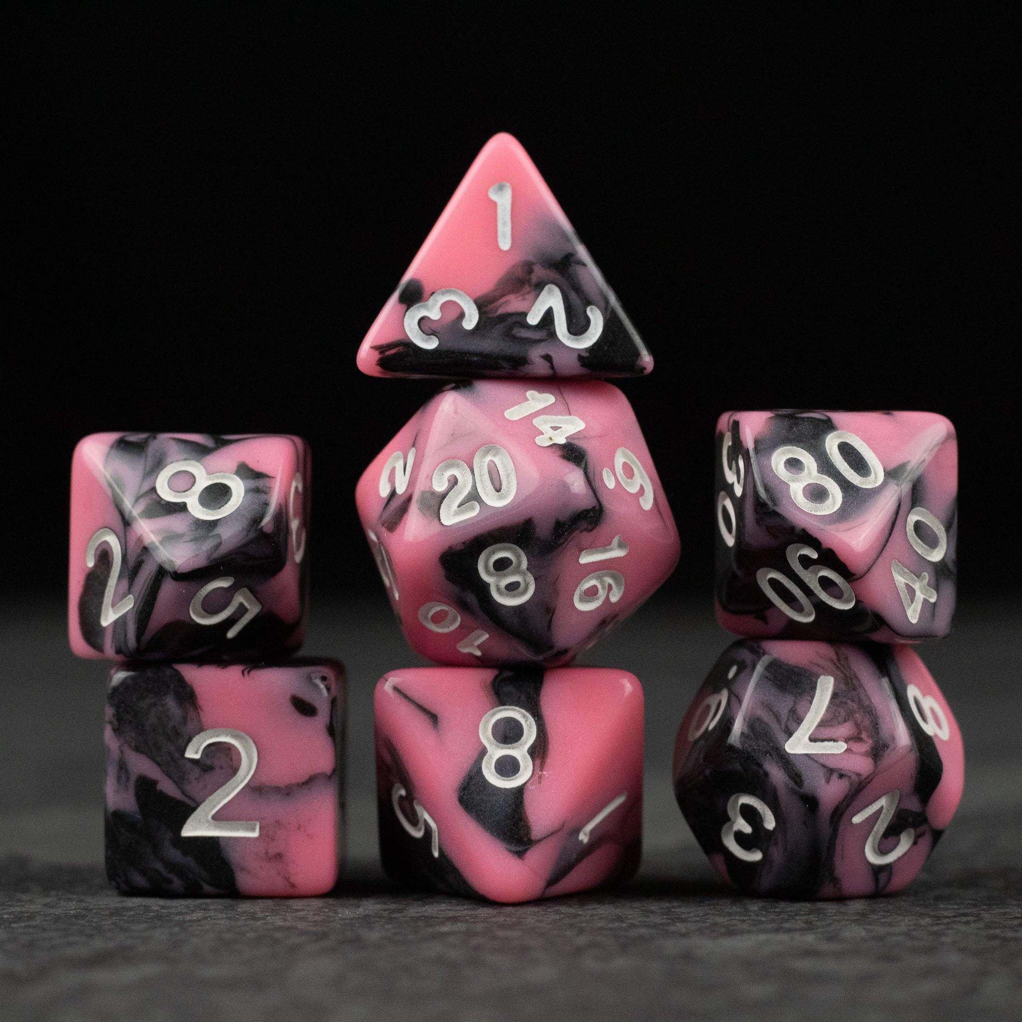 Black & Pink Marbled Dice Set - Black and pink marbled acrylic dice set with white numbering, including various polygon shapes for tabletop games.