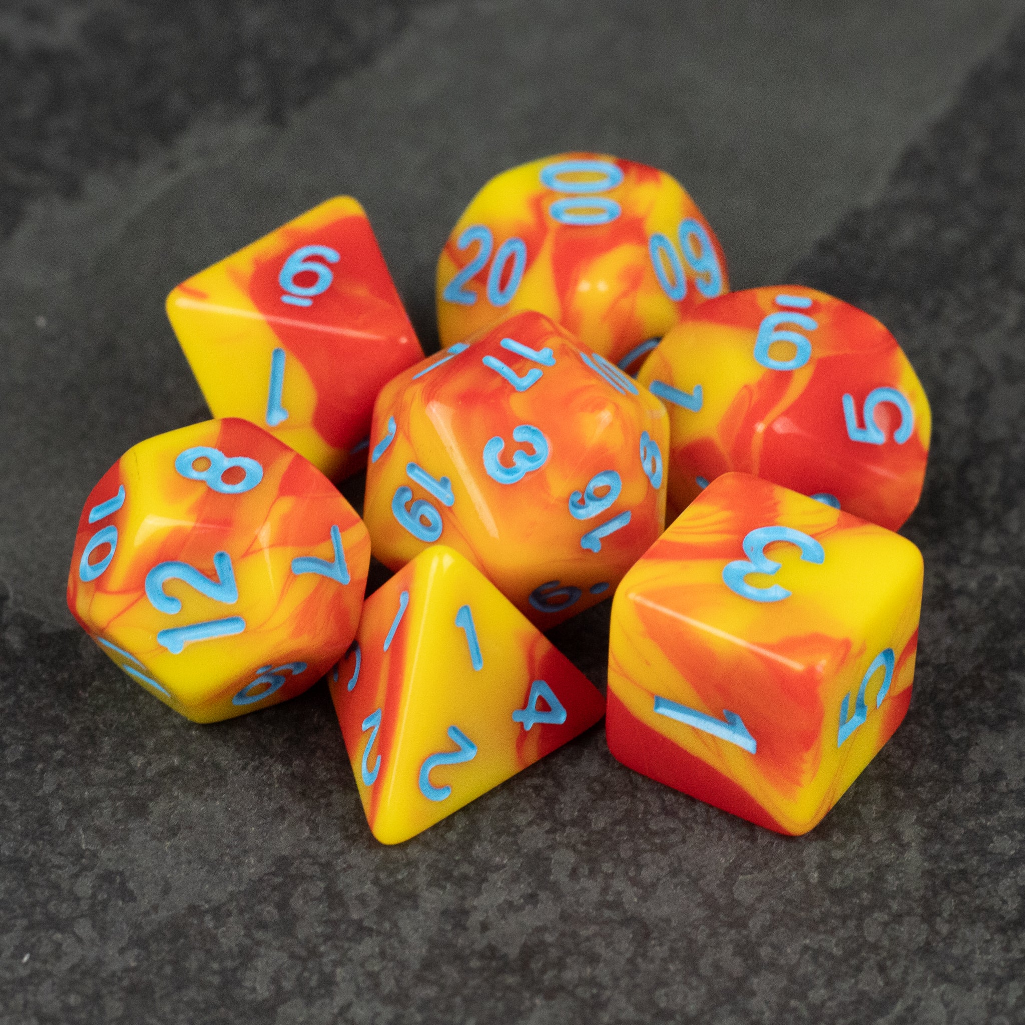 Orange & Yellow Marbled Dice Set - Set of seven acrylic dice with orange and yellow marbled pattern and blue numbers.