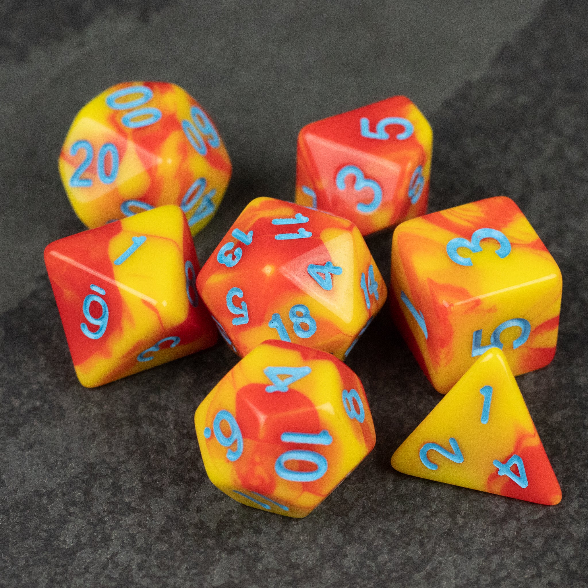 Orange & Yellow Marbled Dice Set - Set of seven orange and yellow marbled acrylic dice with blue numbers, including d20, d12, d10, d8, d6, and d4.