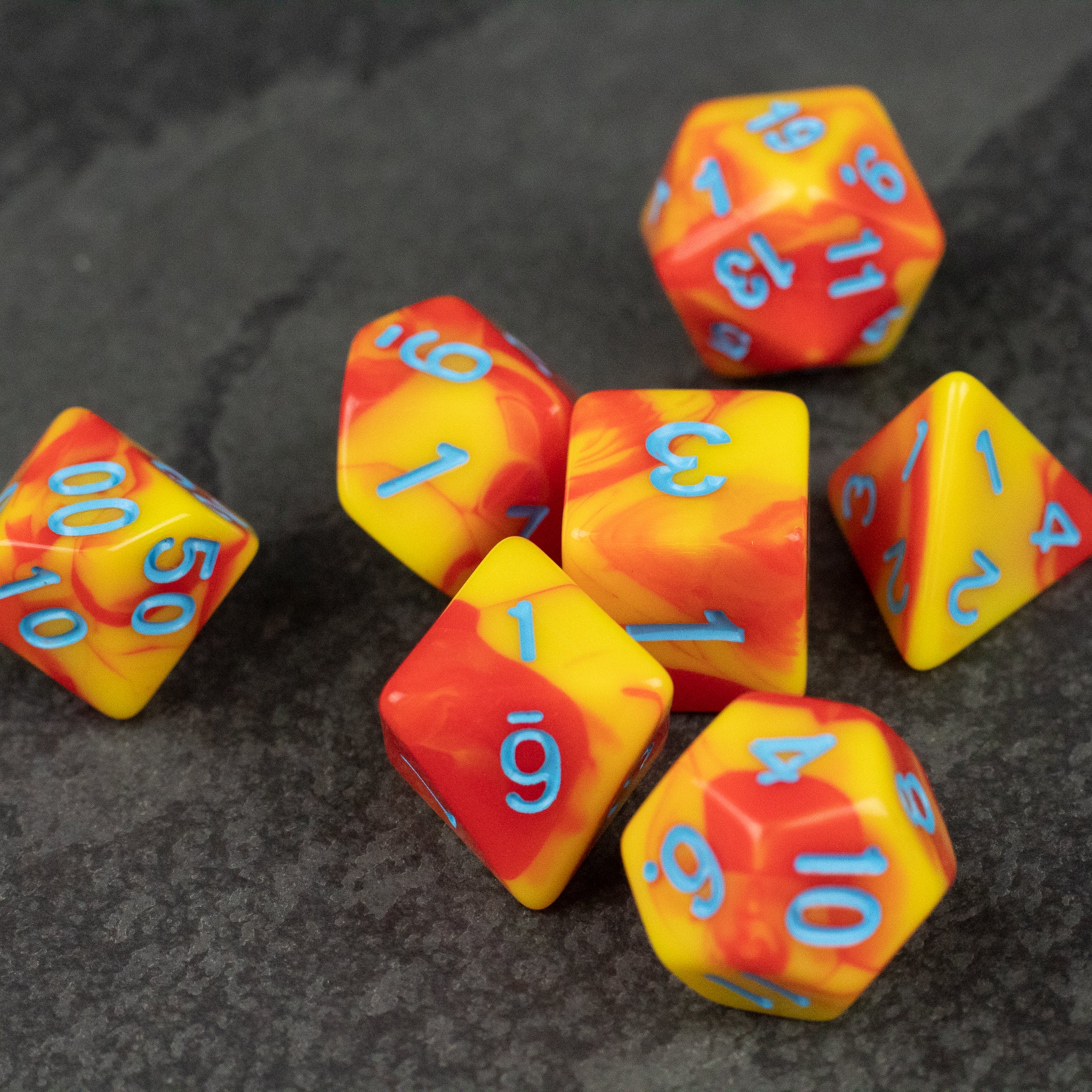 Orange & Yellow Marbled Dice Set - Seven orange and yellow marbled acrylic dice with light blue numbers, including d20, d12, d10, d8, d6, and d4 shapes.