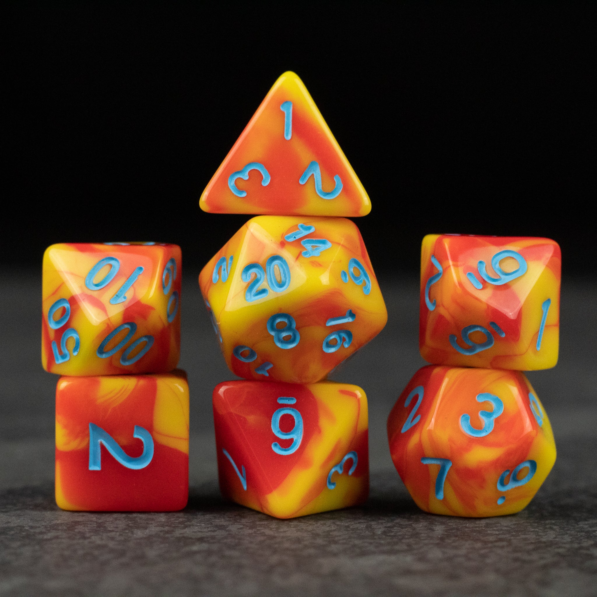 Orange & Yellow Marbled Dice Set - Seven orange and yellow marbled acrylic dice with blue numbers, including d4, d6, d8, d10, d12, and d20 shapes.