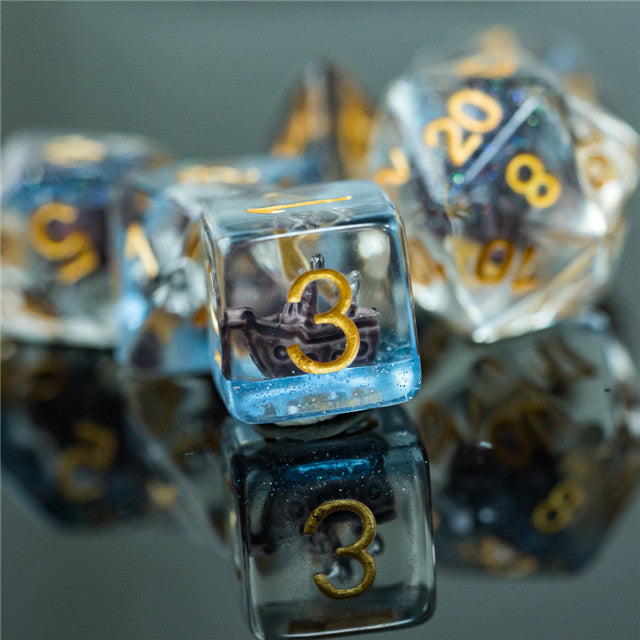 Boat Dice - Clear resin dice with gold numbers and miniature boat figurines inside, including a d20 and a d6.