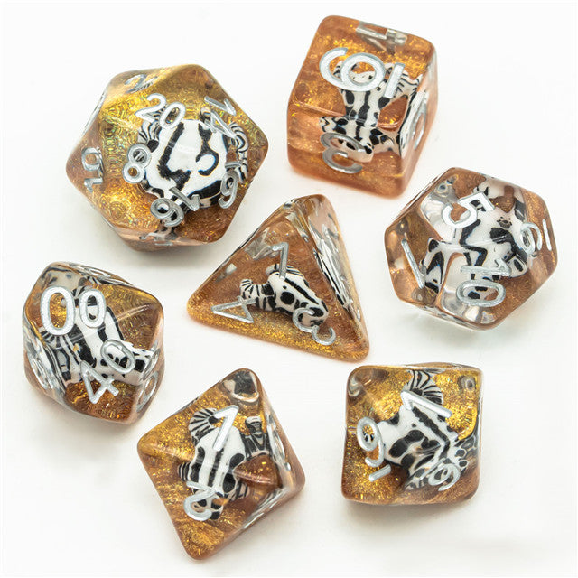 Desert Skull Dice Set - Seven polyhedral dice with translucent amber and gold tones featuring embedded skull designs and white numbering.