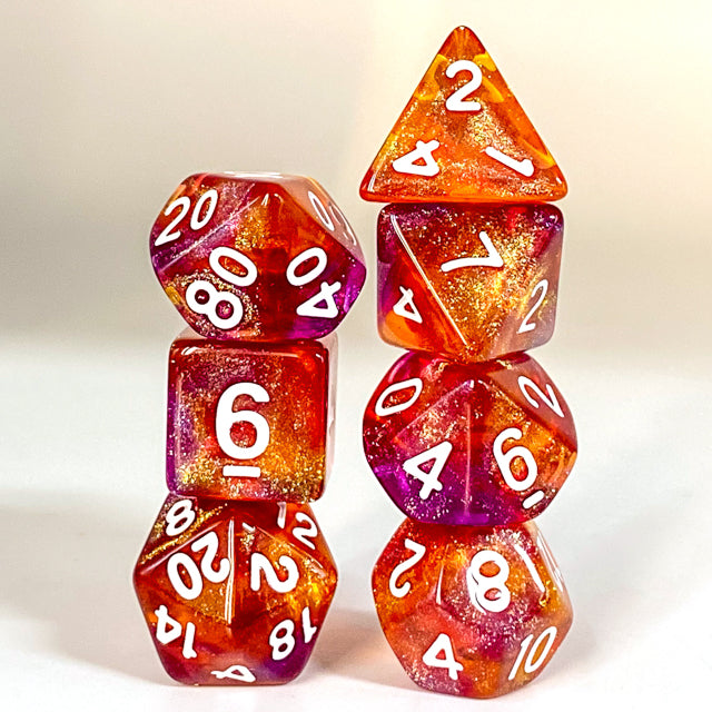 Sunset Glitter Acrylic Dice Set - Set of seven orange and red acrylic dice with white numbers, glittery sunset-inspired design, various shapes including d20,.