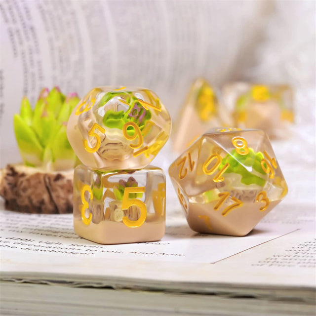Succulent Dice Set - Transparent resin dice set with embedded green succulent plants and gold numbers on white pages.