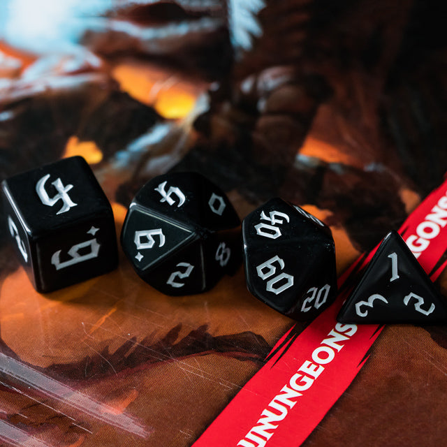 Black Acrylic Dice Set - White - Black acrylic polyhedral dice set with white numbering displayed on a board game surface.