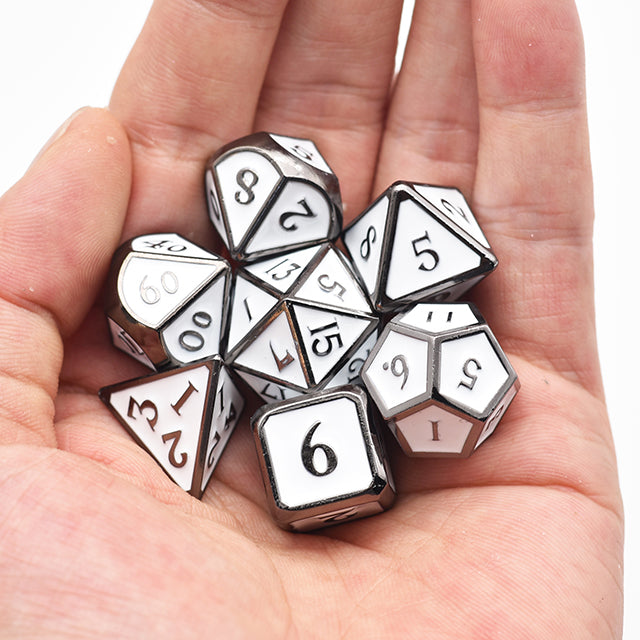 White Enameled Metal Dice Set - Set of white enameled metal polyhedral dice with black numbers held in a hand.