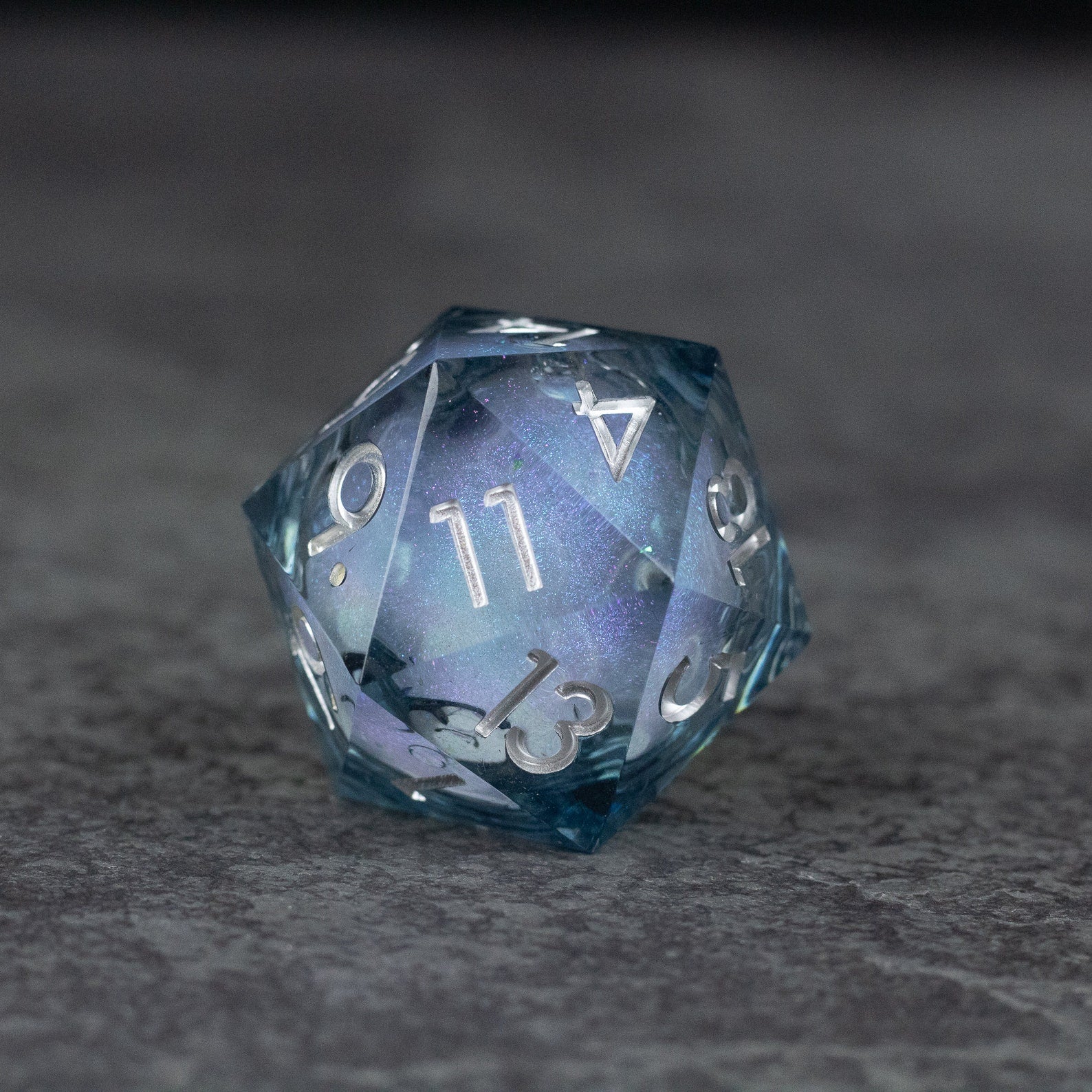 33mm Liquid Core D20 Chonk - Midnight Blue - 33mm translucent blue D20 dice with liquid core and white numbering on gray surface.