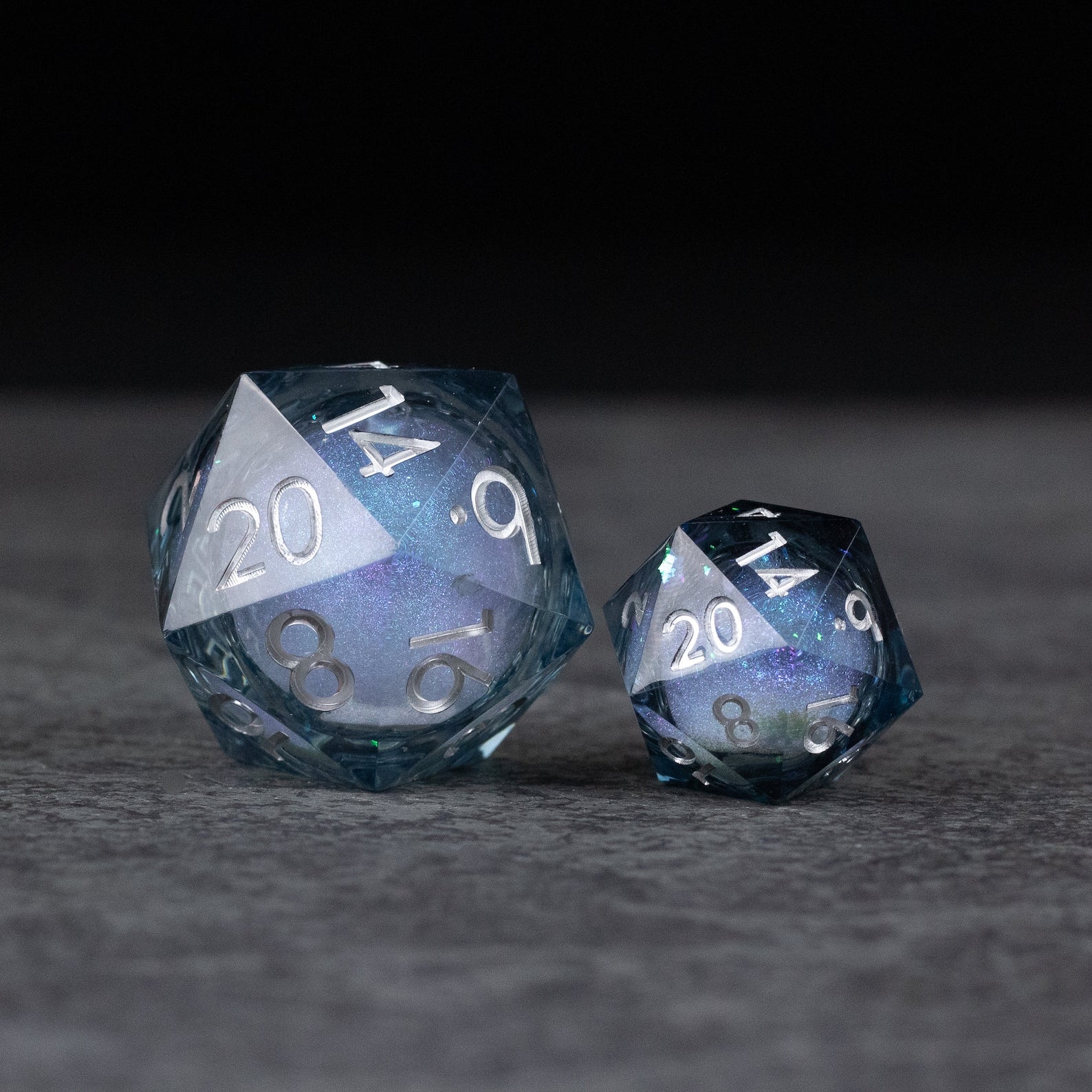 33mm Liquid Core D20 Chonk - Midnight Blue - Two blue 20-sided dice with shimmering liquid cores, one large 33mm and one smaller, both with silver numbers.