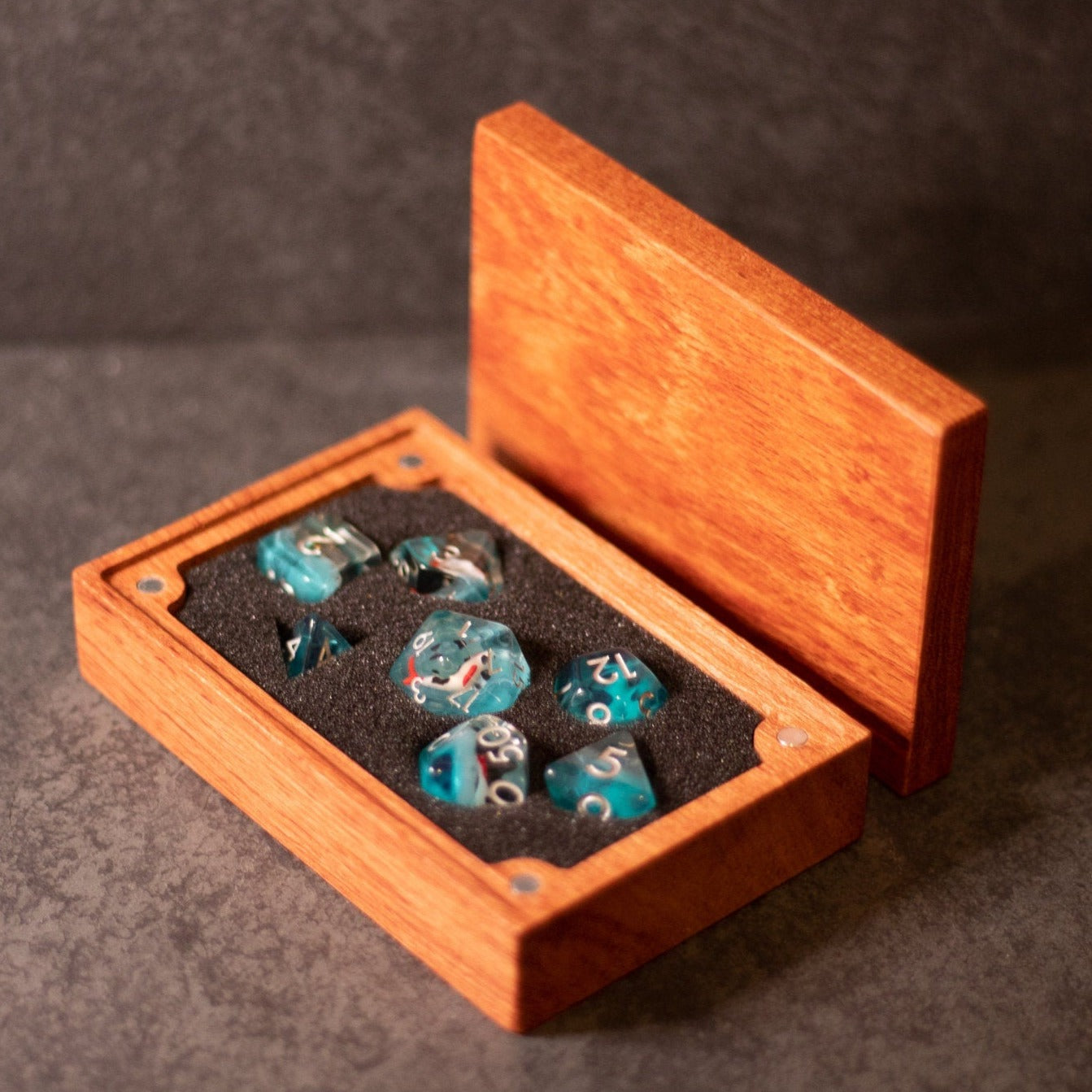 Koi Fish Dice Set - Set of seven turquoise dice with koi fish designs in a brown wooden box with black foam lining and an open lid.