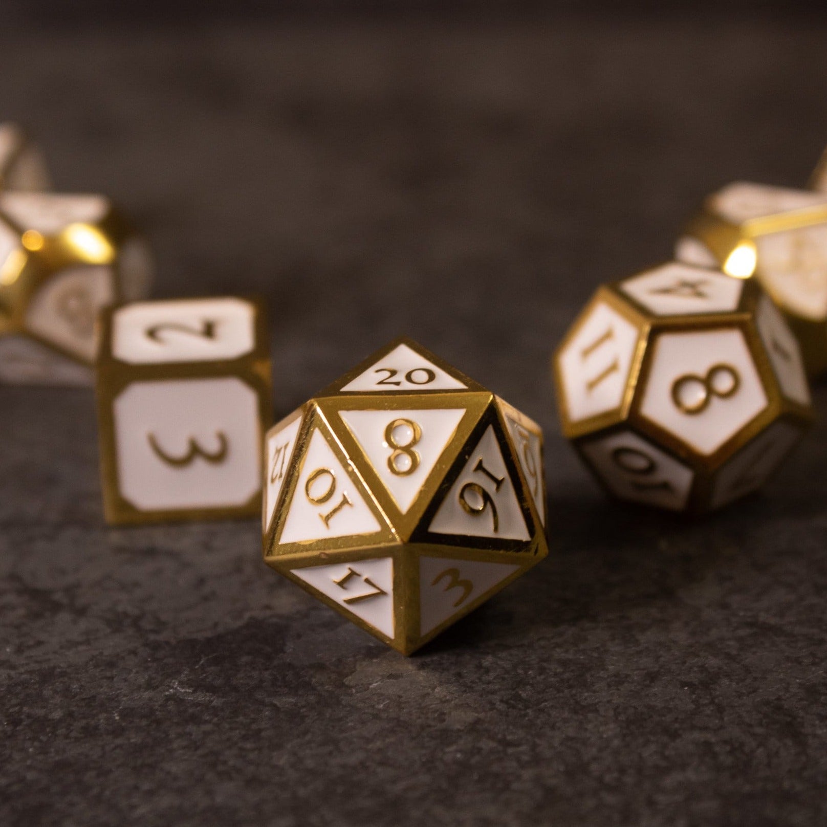 Honor - White & Gold Metal Dice - Set of white and gold metal polyhedral dice with engraved numbers, including a 20-sided die in focus.