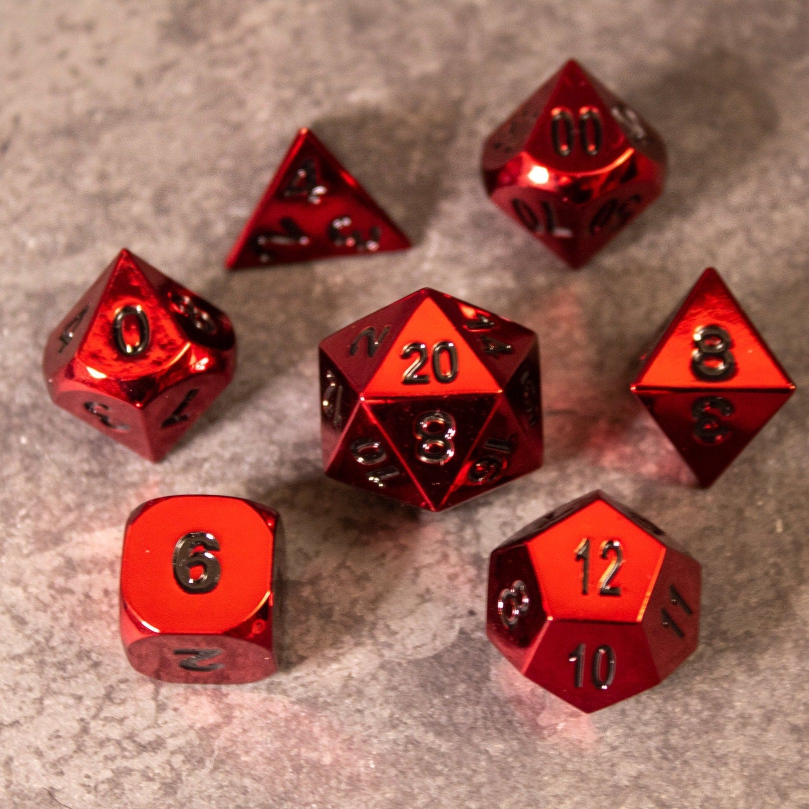Rage - Red Metal Dice - Set of seven shiny red metal dice with black numbers, including d4, d6, d8, d10, d12, d20, and percentile dice on a textured .
