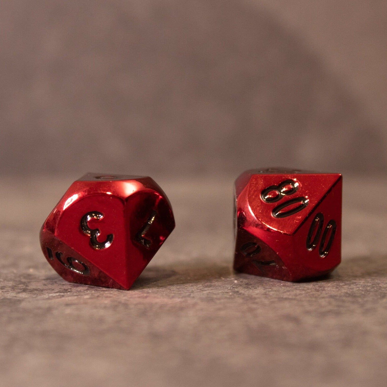 Rage - Red Metal Dice - Two red metal dice with black engraved numbers, one showing the number 20, on a neutral surface.