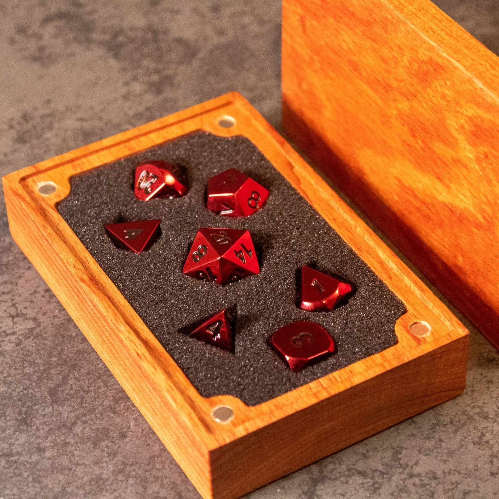 Rage - Red Metal Dice - Set of seven red metal dice with black numbers displayed in a wooden box with black foam lining.