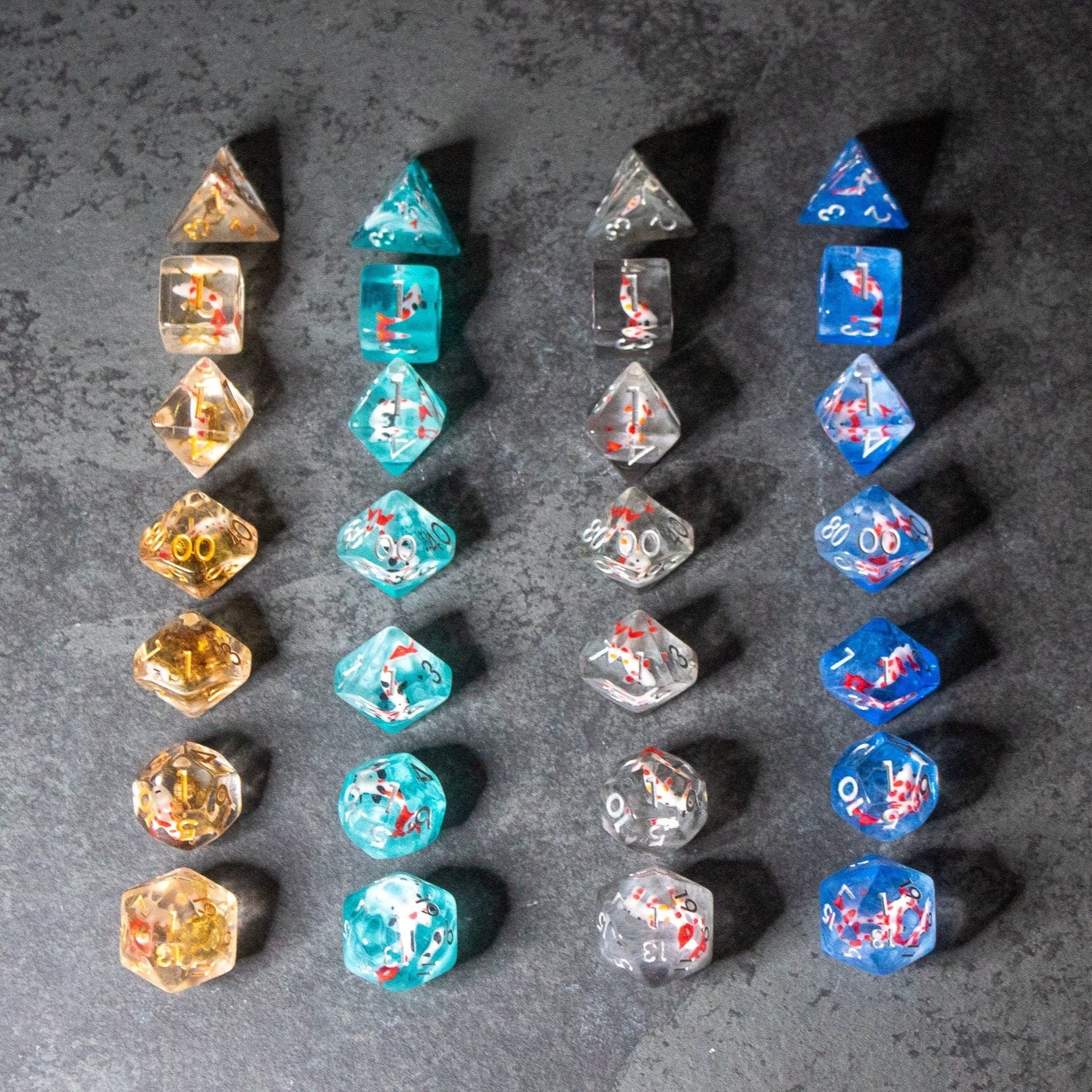 Koi Fish Dice Set - Four vertical rows of six translucent polyhedral dice, featuring koi fish and aquatic designs in gold, turquoise, smoky.