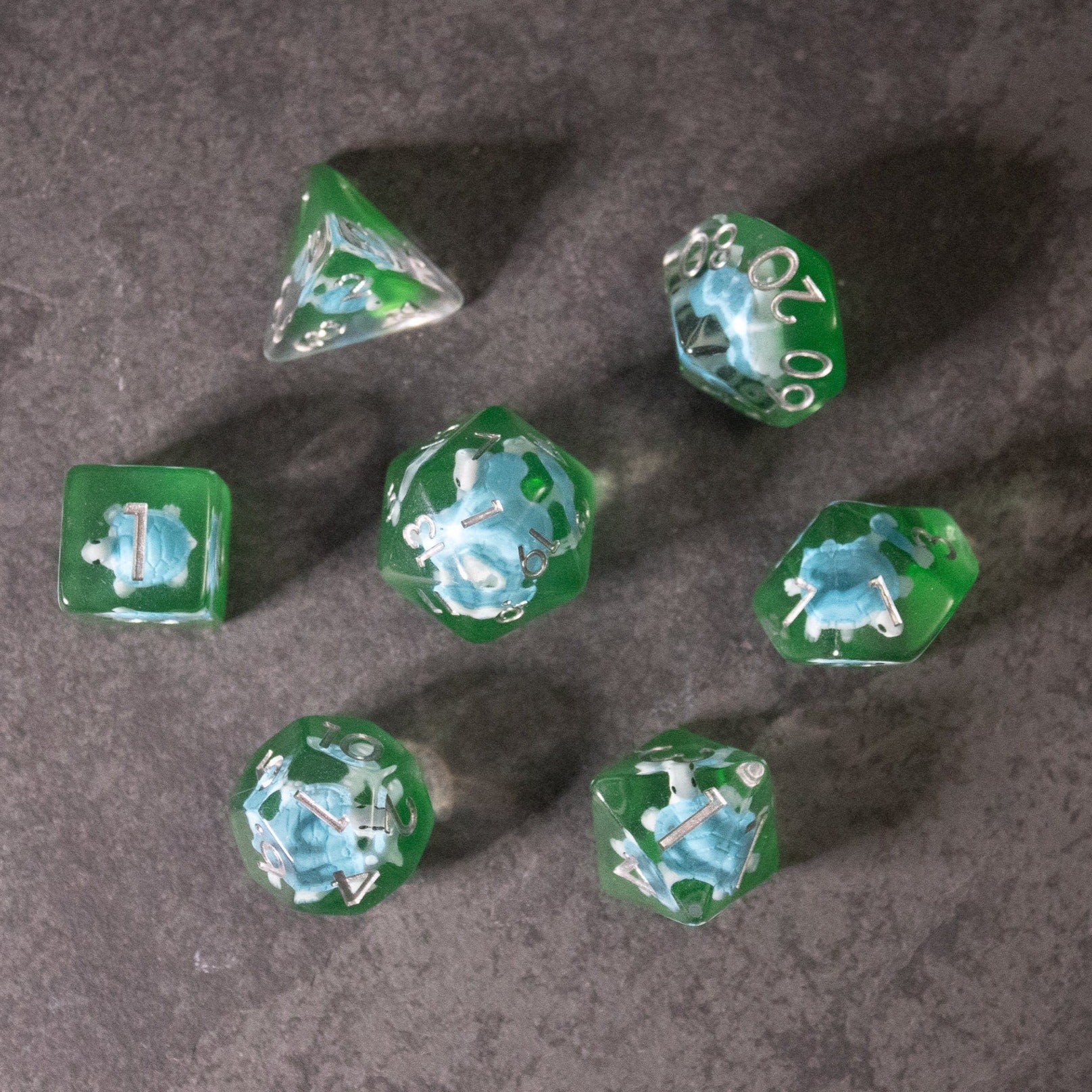 Blue Turtle Dice - Set of seven transparent green polyhedral dice with blue turtle designs and white numbers on each face.
