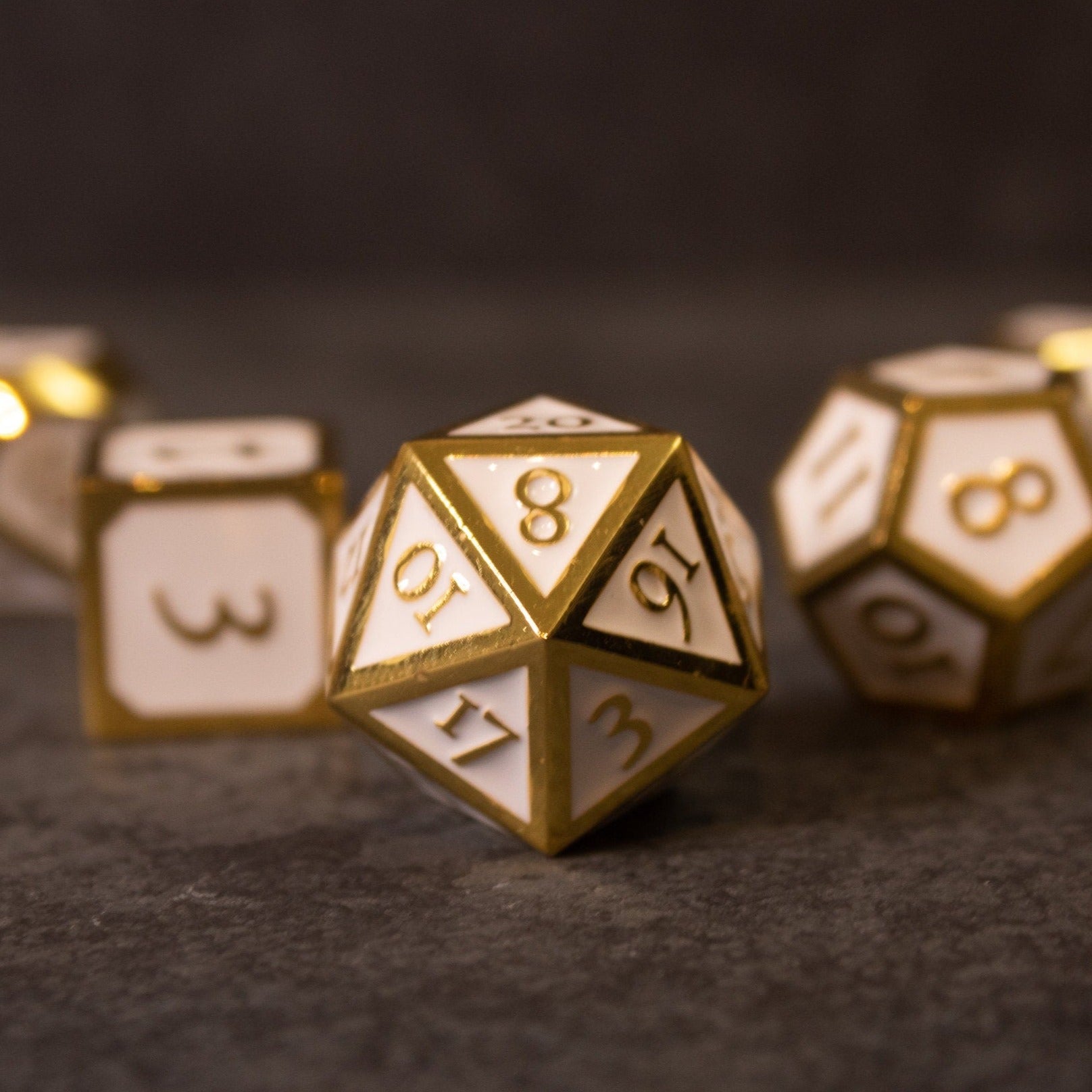 Honor - White & Gold Metal Dice - White and gold metal 20-sided die with engraved numbers on dark surface.