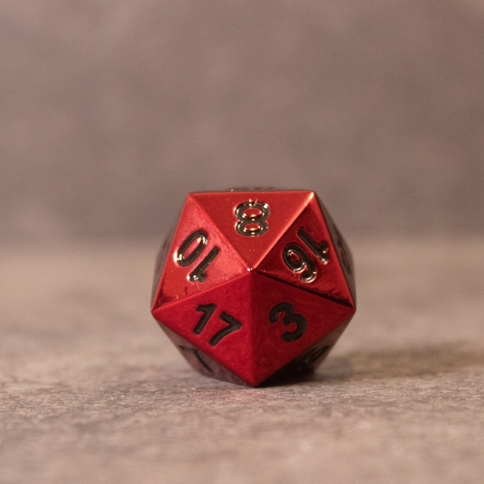 Rage - Red Metal Dice - Red metal 20-sided die with black numbers on a neutral surface.