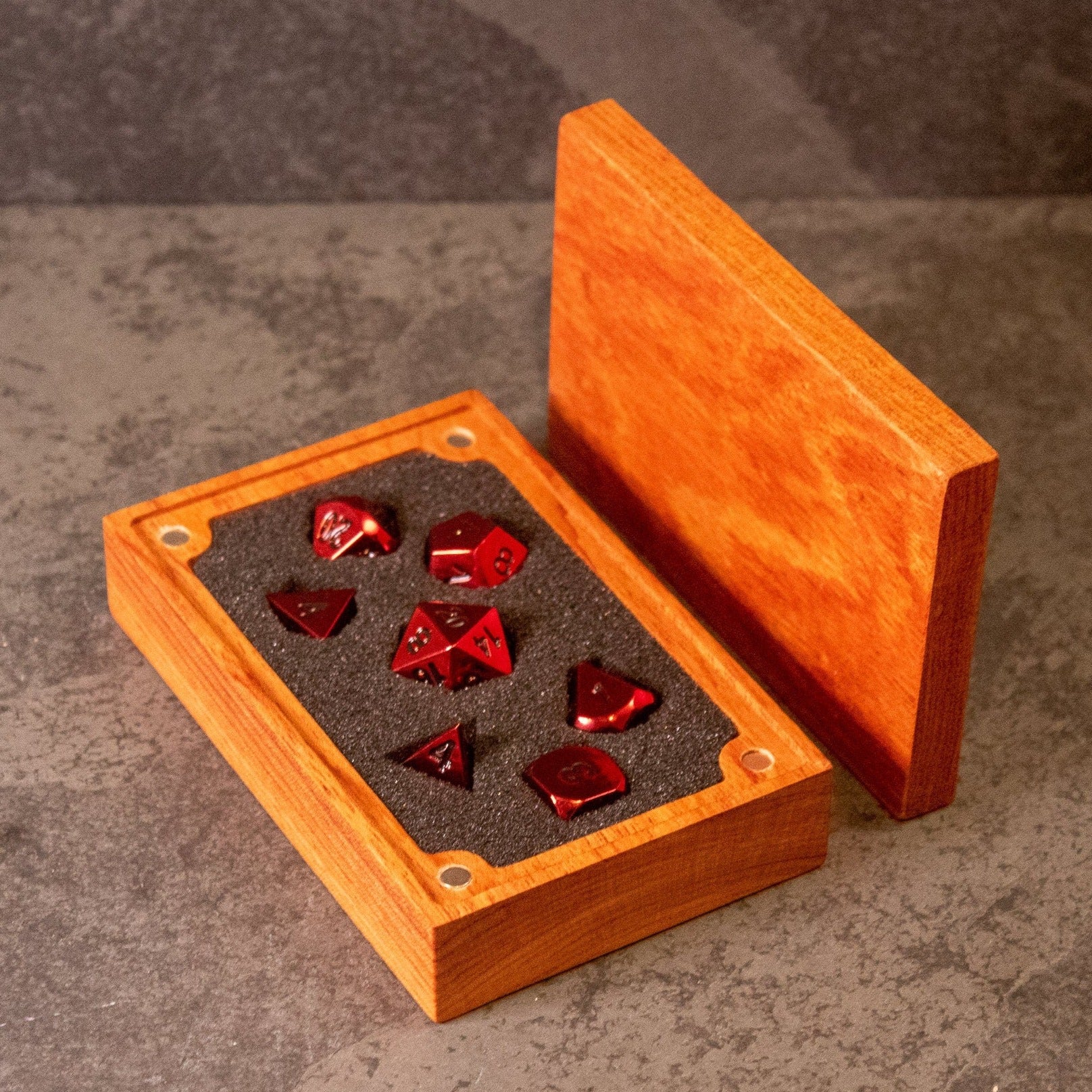 Rage - Red Metal Dice - Red metal gaming dice set in black foam insert inside an open wooden box with brass corner accents.