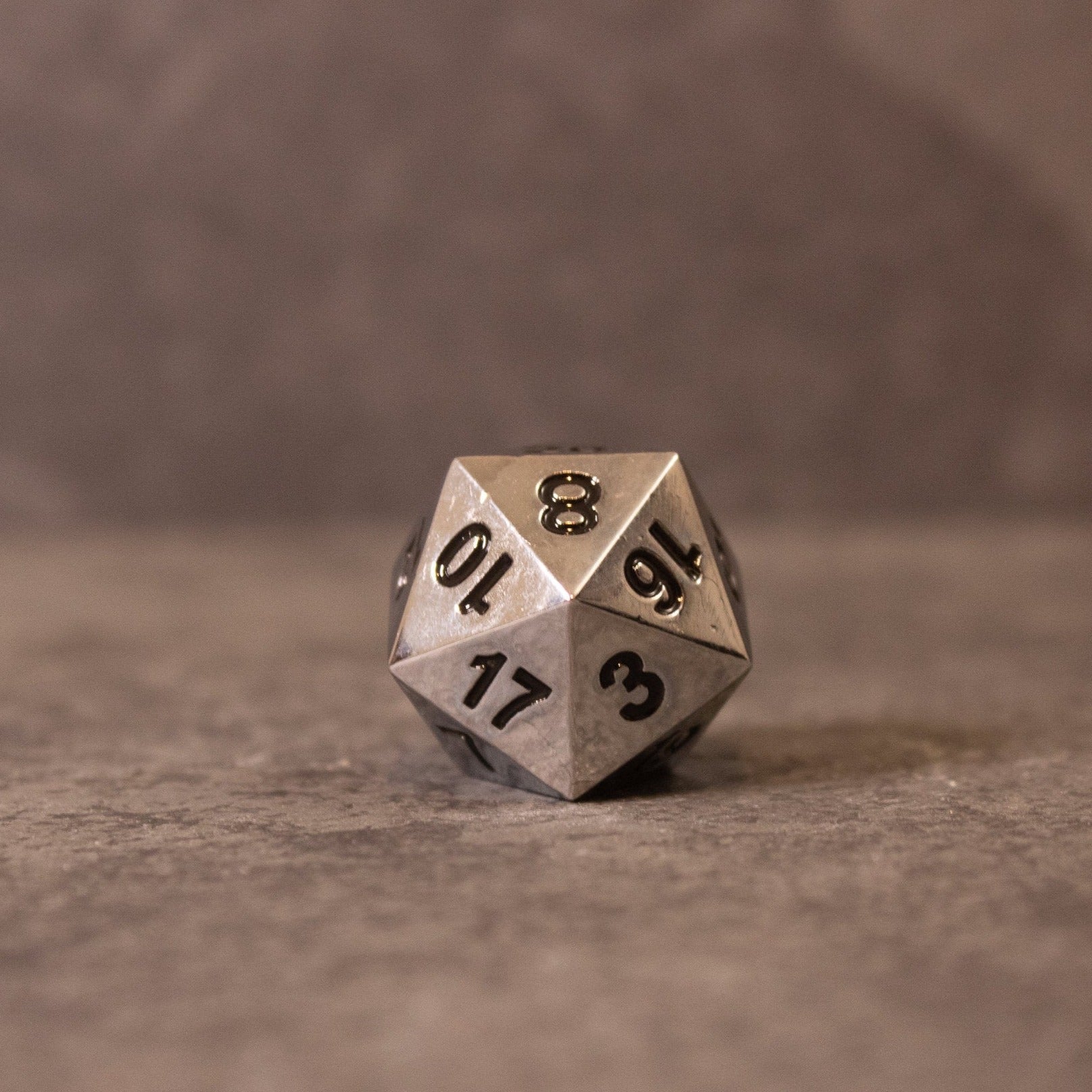 Purity - Silver Metal - Silver metal 20-sided dice with black engraved numbers on a textured gray surface.