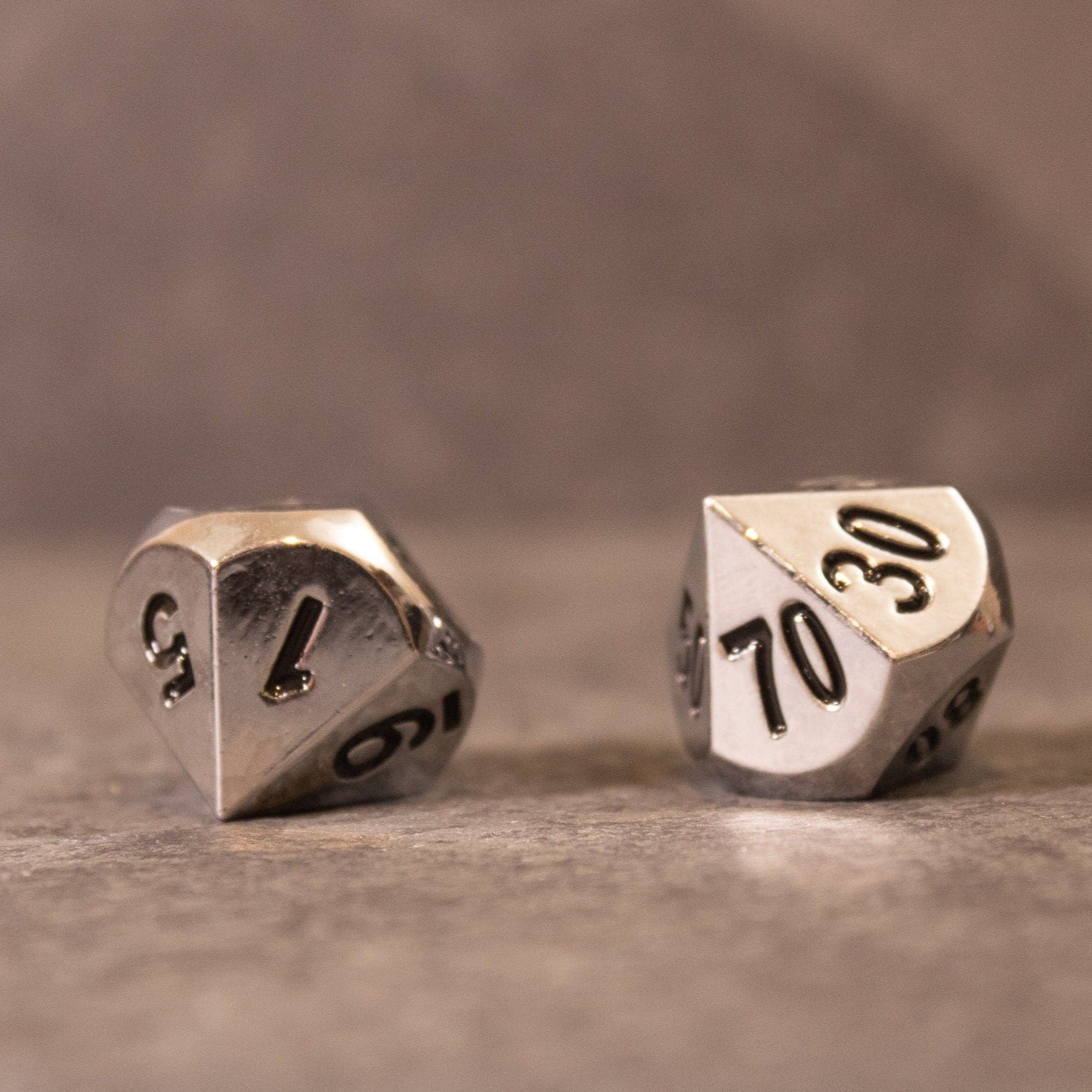 Purity - Silver Metal - Two silver metal dice with black numbering, including a d10 and a percentile d10, on a gray surface.