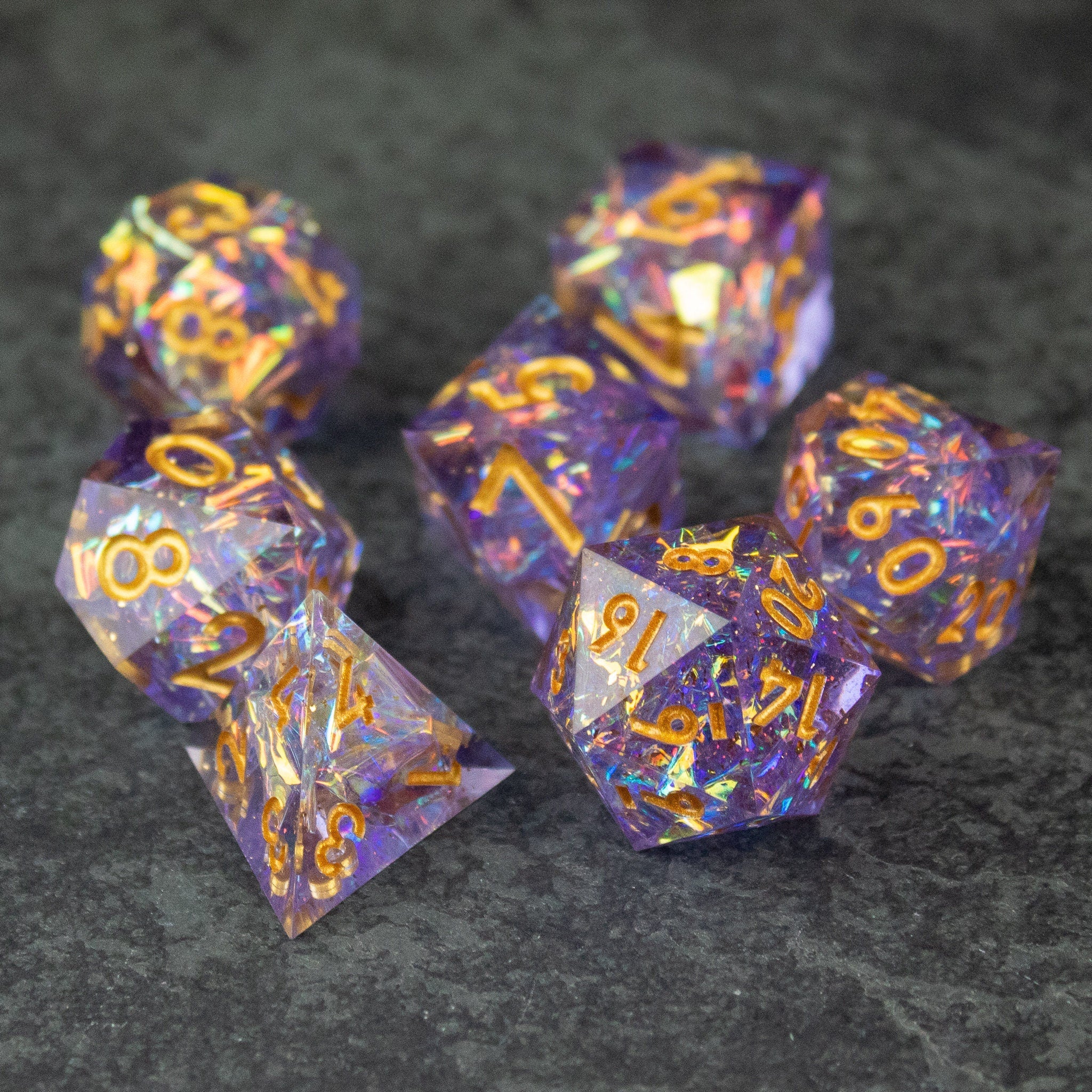 Feywild DnD Dice Set - Sharp Edge Dice for D&D - Purple and gold sharp-edged DnD dice set with glittery, translucent design on dark surface.