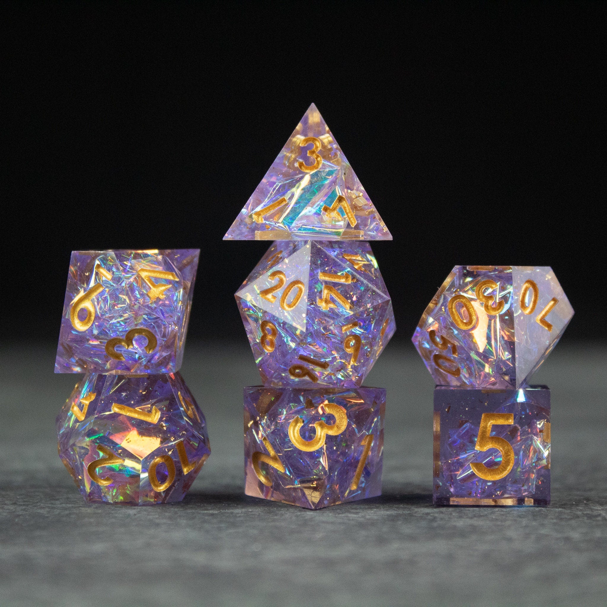 Feywild DnD Dice Set - Sharp Edge Dice for D&D - Set of translucent purple DnD dice with gold sharp-edged numbers and colorful iridescent flakes.