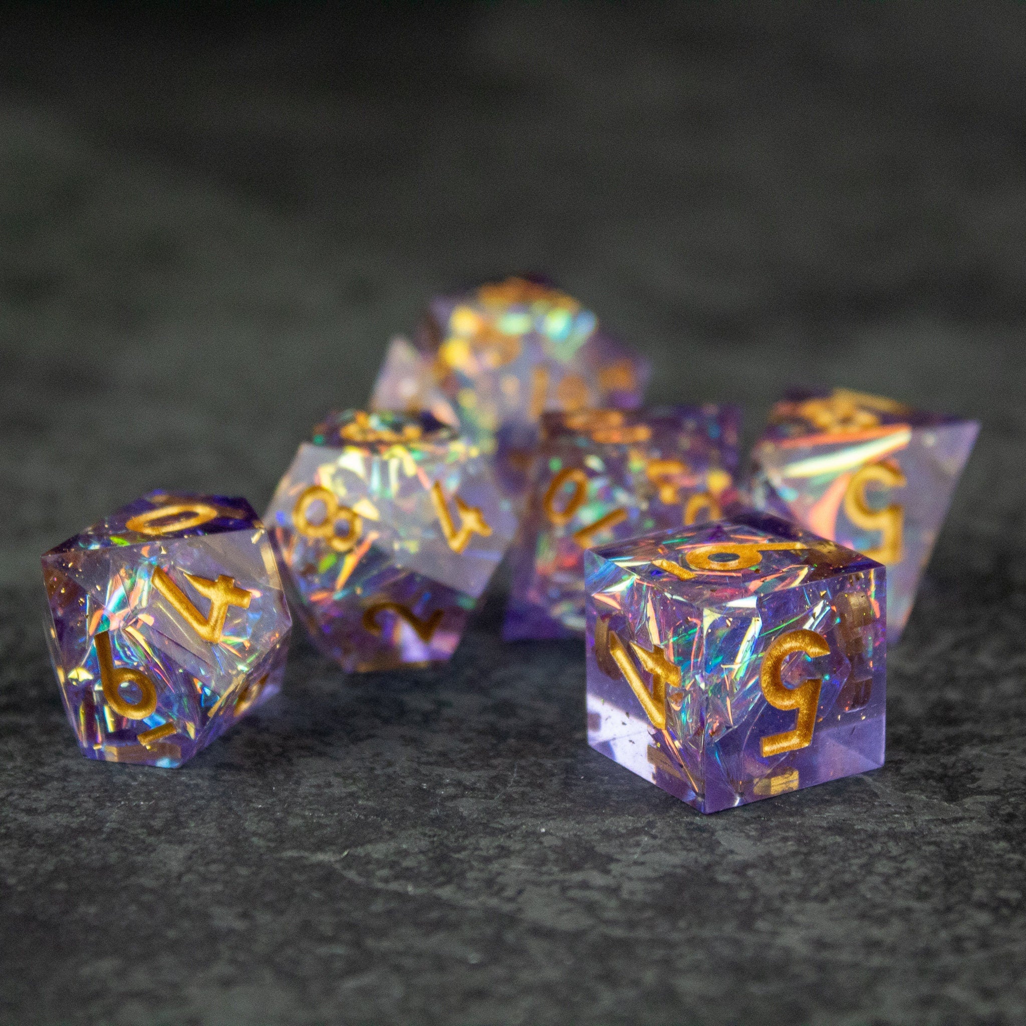 Feywild DnD Dice Set - Sharp Edge Dice for D&D - Translucent purple DnD dice set with sharp edges and gold numbers on gray surface.