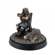 Mysterious Stranger and Hound - Figurine of cloaked man in teal and brown leather holding a pipe, seated next to a large gray and brown hound on textured.