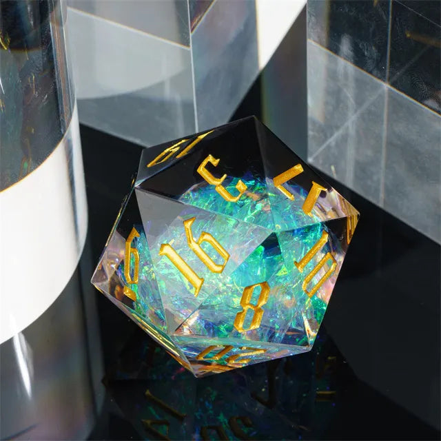 33mm Clear & Black Shimmer D20 - 33mm clear d20 dice with black edges and gold numbers, featuring a shimmering blue and green core.