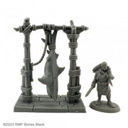 Shark Butcher - Gray resin miniature of a shark hanging from a wooden frame tied with ropes, next to a cloaked figure holding a cleaver.