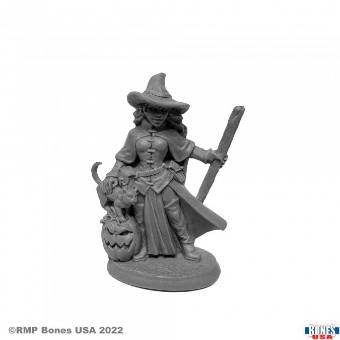 Cynthia the Wicked Witch - Gray resin miniature of a witch wearing a wide-brimmed hat and long dress, holding a staff with a carved jack-o'-lantern at.