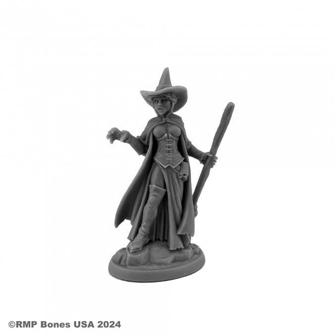 Wild West Oz - Wicked Witch - Gray resin miniature of a witch in a flowing dress and cape, wearing a pointed hat and holding a broomstick upright.