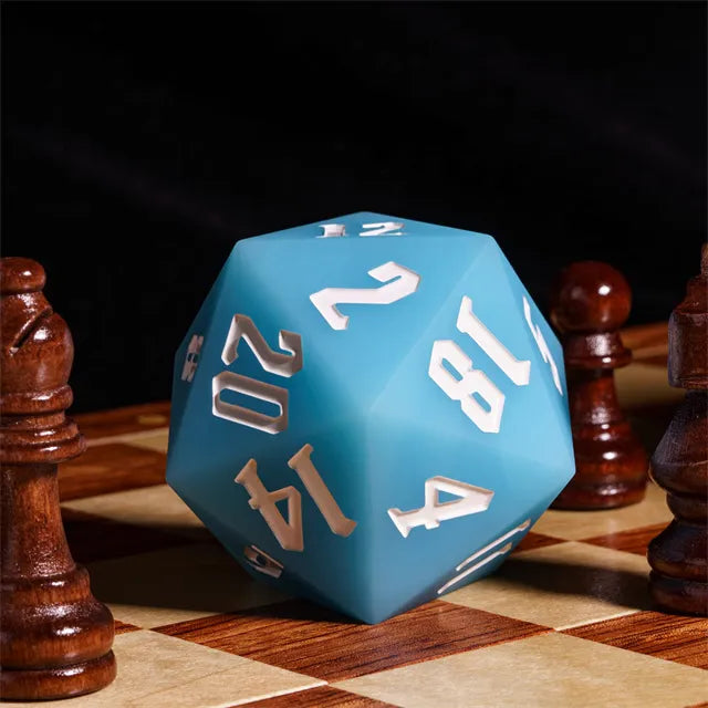 Giant Bouncy D20 - Glow In The Dark Blue - Large blue 20-sided die with white numbers, matte finish, resting on a wooden chessboard.