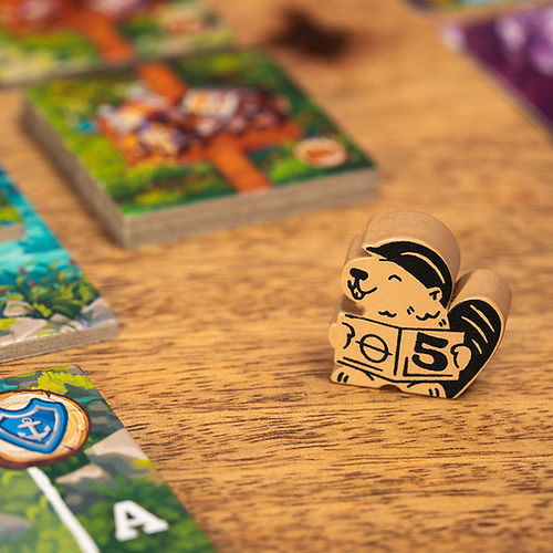 Timber Town - Wooden beaver game piece with a number 5 and cartoon details on a wood table, surrounded by colorful game cards.