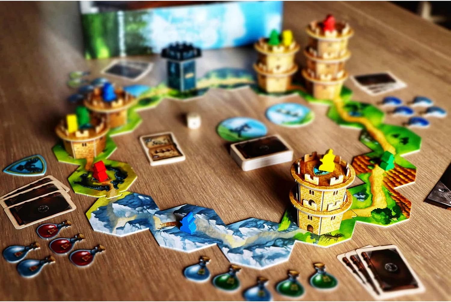 Wandering Towers - Colorful wooden tower pieces on circular cardboard bases arranged on a board with island and water tile sections, surrounded