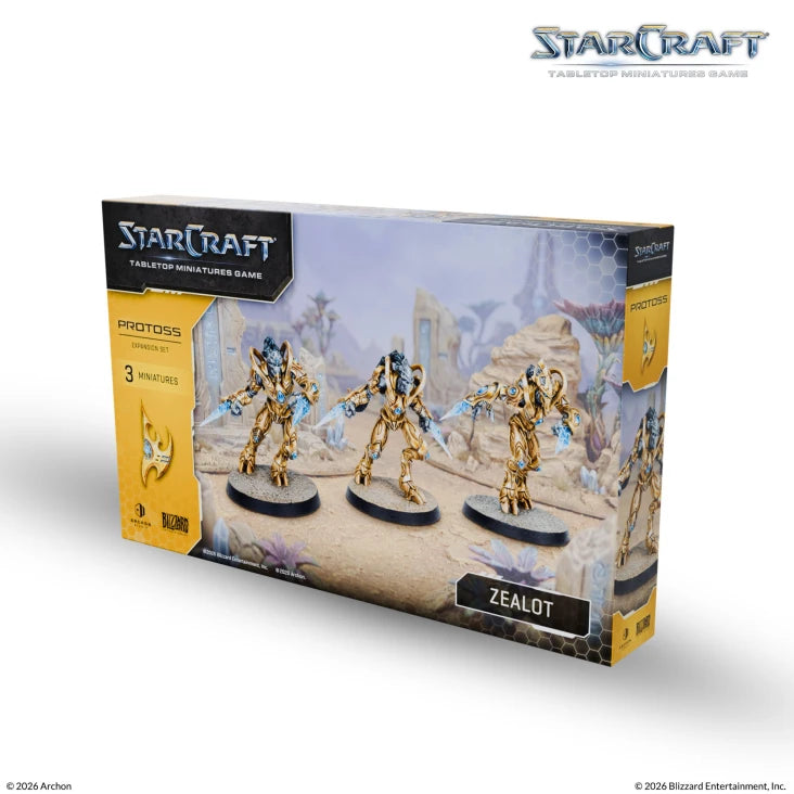 StarCraft TMG: Protoss - Zealot (PREORDER) - Three detailed beige and gold Protoss Zealot miniatures with blue energy blades on a sandy desert game board backdrop in a.