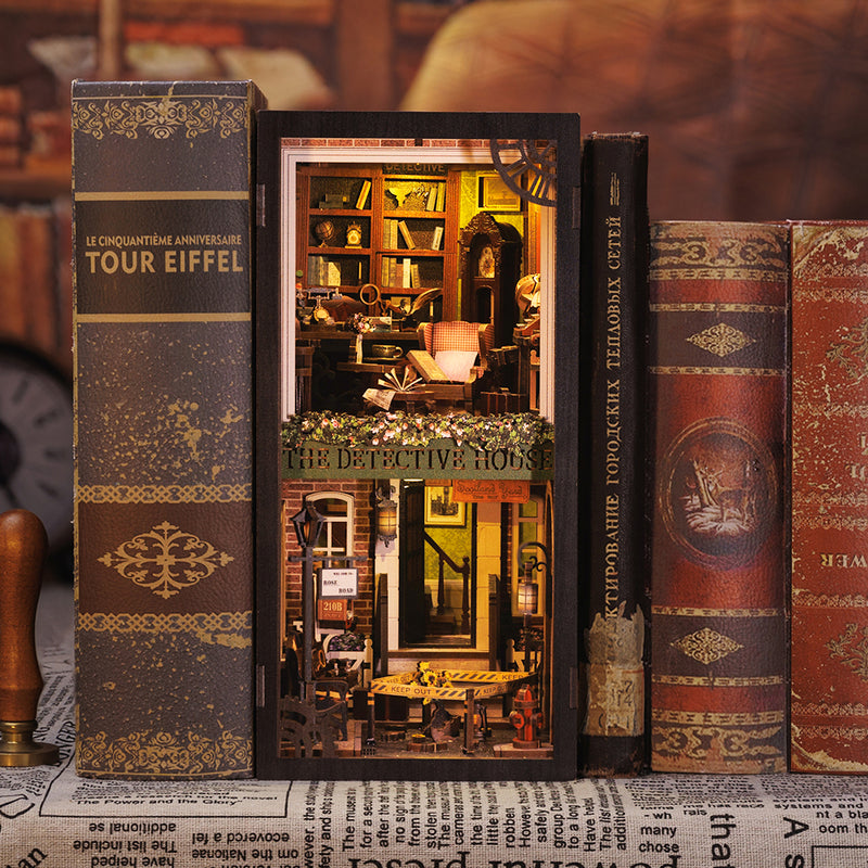 Rose Detective Agency Book Nook (PREORDER) - Intricately detailed miniature book nook with warm lighting, wooden shelves, armchair, and detective-themed decor between.
