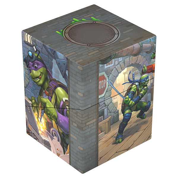Ultimate Guard RTE Boulder 100+ Deck Case: Teenage Mutant Ninja Turtles - Turtle Lair - Square gray deck case with stone wall design featuring Teenage Mutant Ninja Turtles in action scenes on sides.