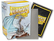 Dragon Shield 100ct Box - Matte Silver - Matte silver card sleeve resting against white box with dragon illustration and black Dragon Shield card back visible.