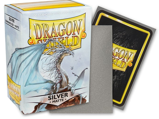 Dragon Shield 100ct Box - Matte Silver - Matte silver card sleeve resting against white box with dragon illustration and black Dragon Shield card back visible.