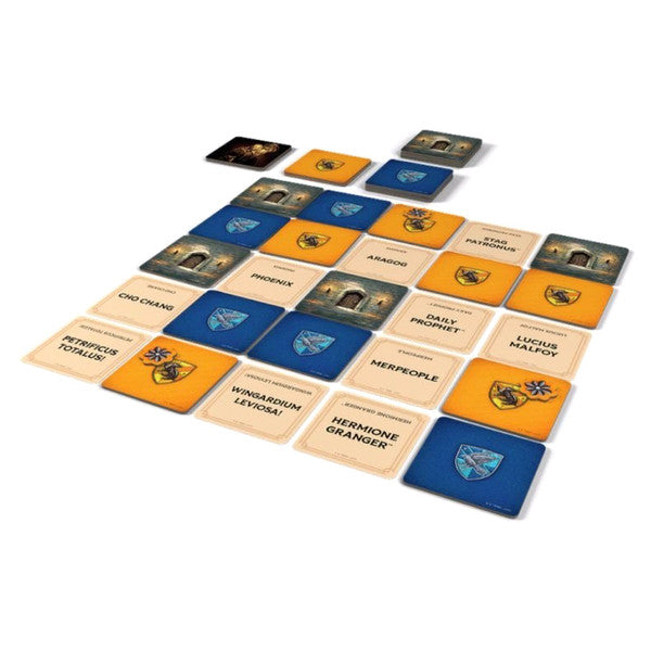 Codenames: Back to Hogwarts (PREORDER) - Square game cards in blue, orange, and beige featuring Hogwarts house crests and character names arranged in a grid pattern.