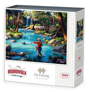Boardwalk 500 Piece Puzzle: Fly Fishing - 500-piece puzzle box featuring colorful fly fishing scene with a fisherman in a river near a waterfall and forest.