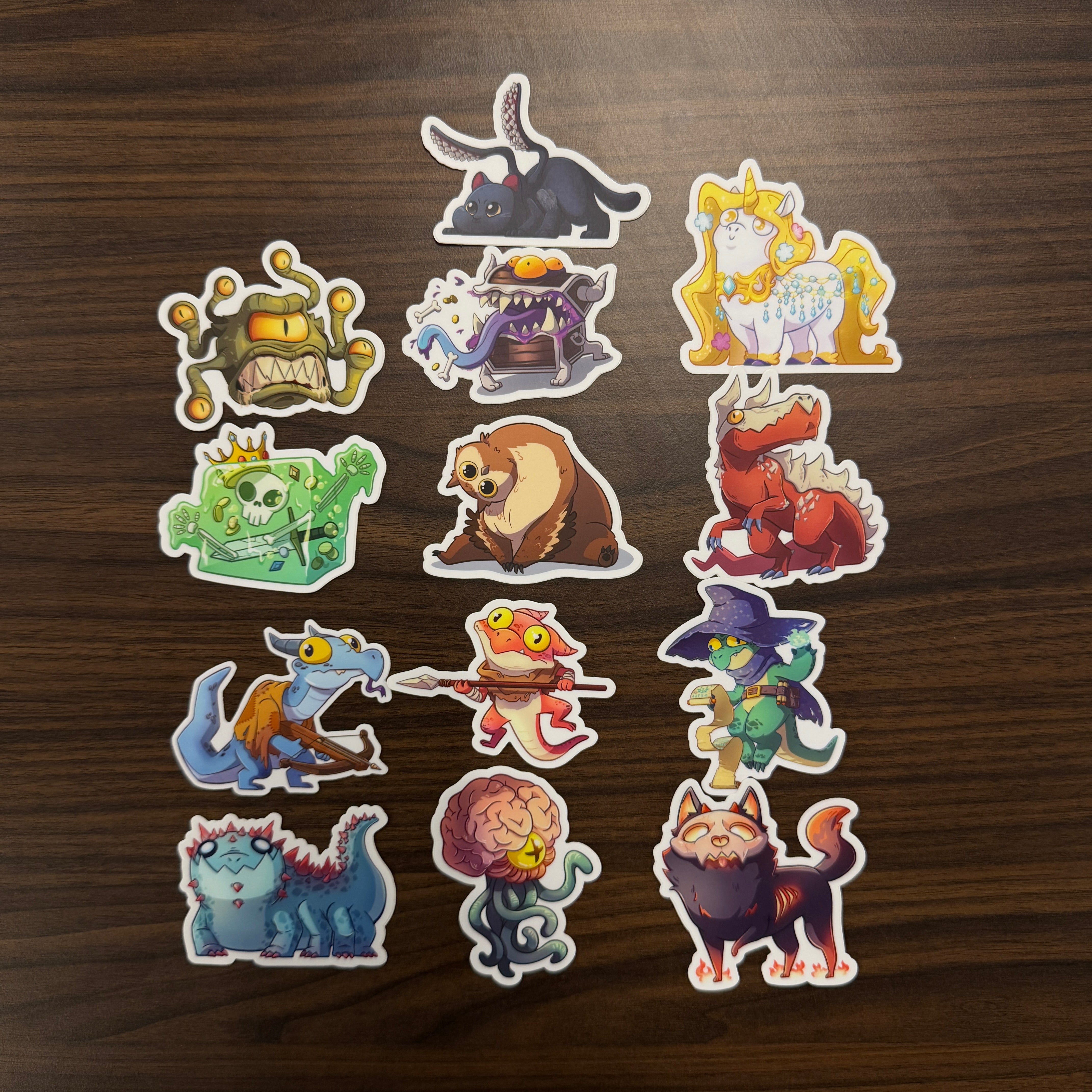 D&D Monsters Sticker Pack - Colorful D&D monster-themed stickers featuring various fantasy creatures with bold outlines on a wooden surface.