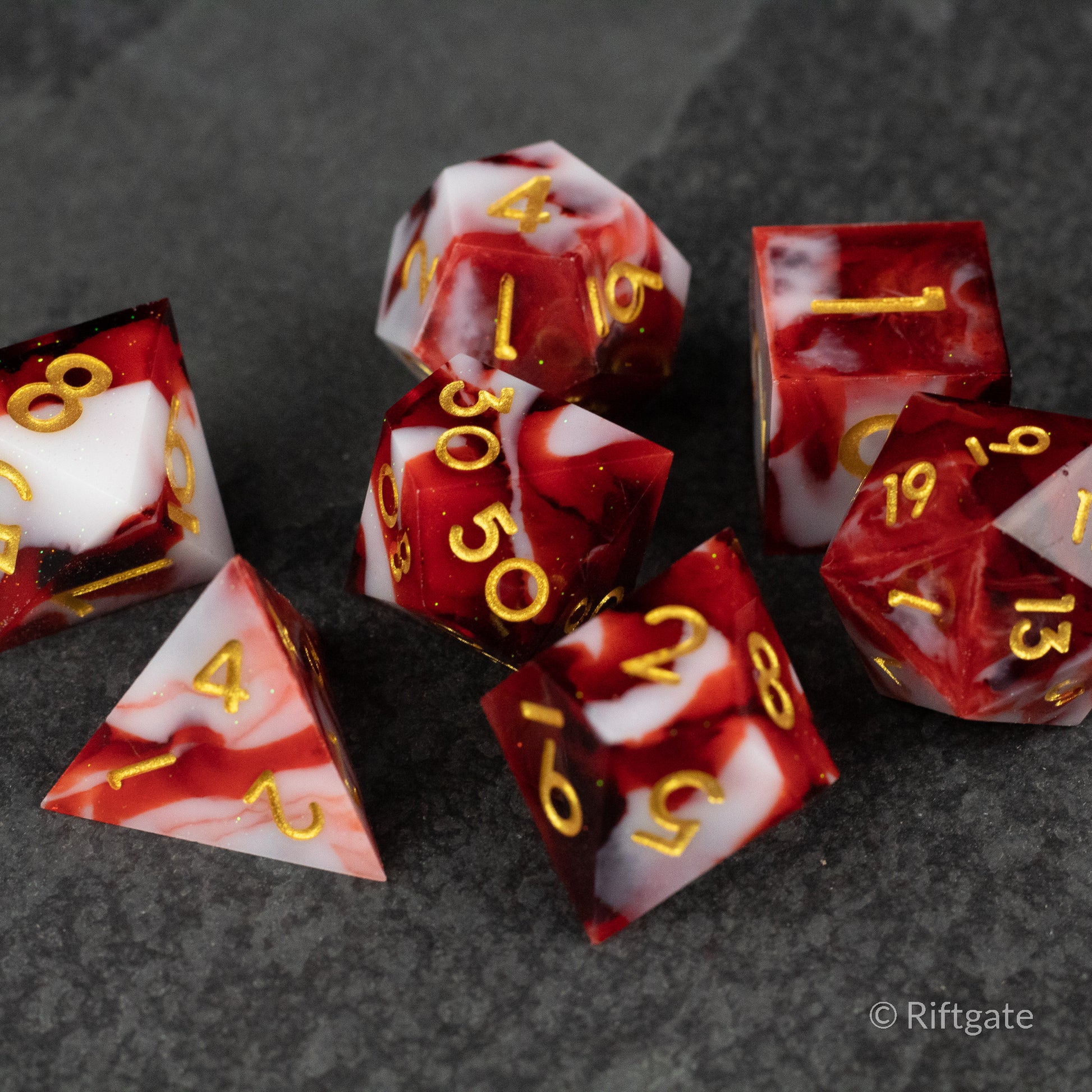 Blood and Snow Dice Set - Red and white marbled sharp edge polyhedral dice set with gold numbers, including d4, d6, d8, d10, d12, and d20.